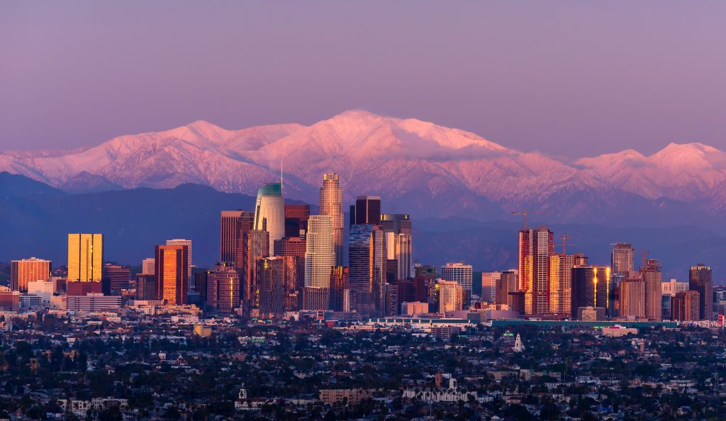 Los Angeles skyline with snow-capped mountains at sunset representing top social media agencies in California