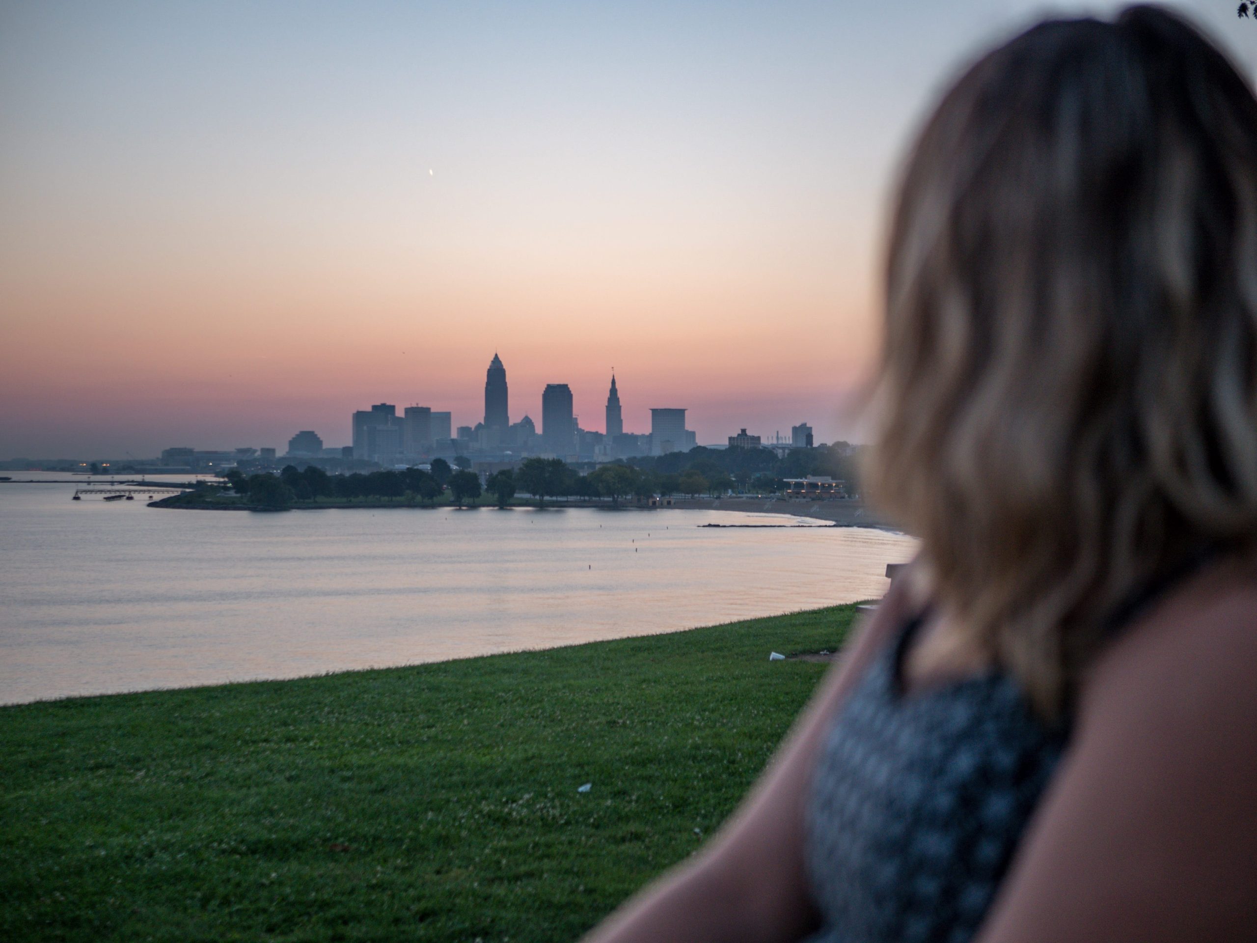 View of the Cleveland skyline at sunrise with a person in the foreground, representing top digital marketing agencies in Ohio helping local brands grow online.