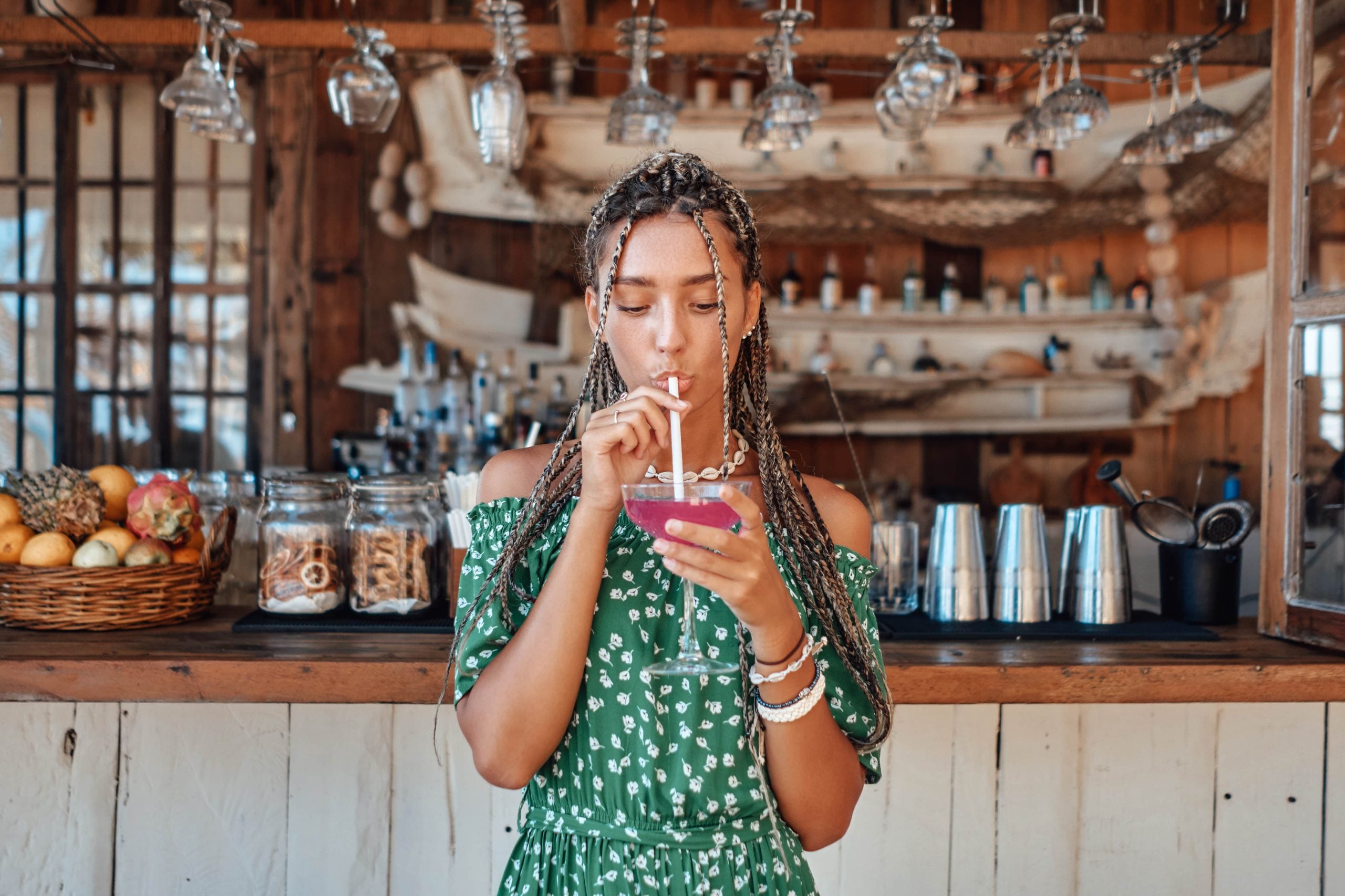 Young woman drinking a colorful beverage at a bar, captured in a casual moment often seen in influencer content for food and beverage brands.