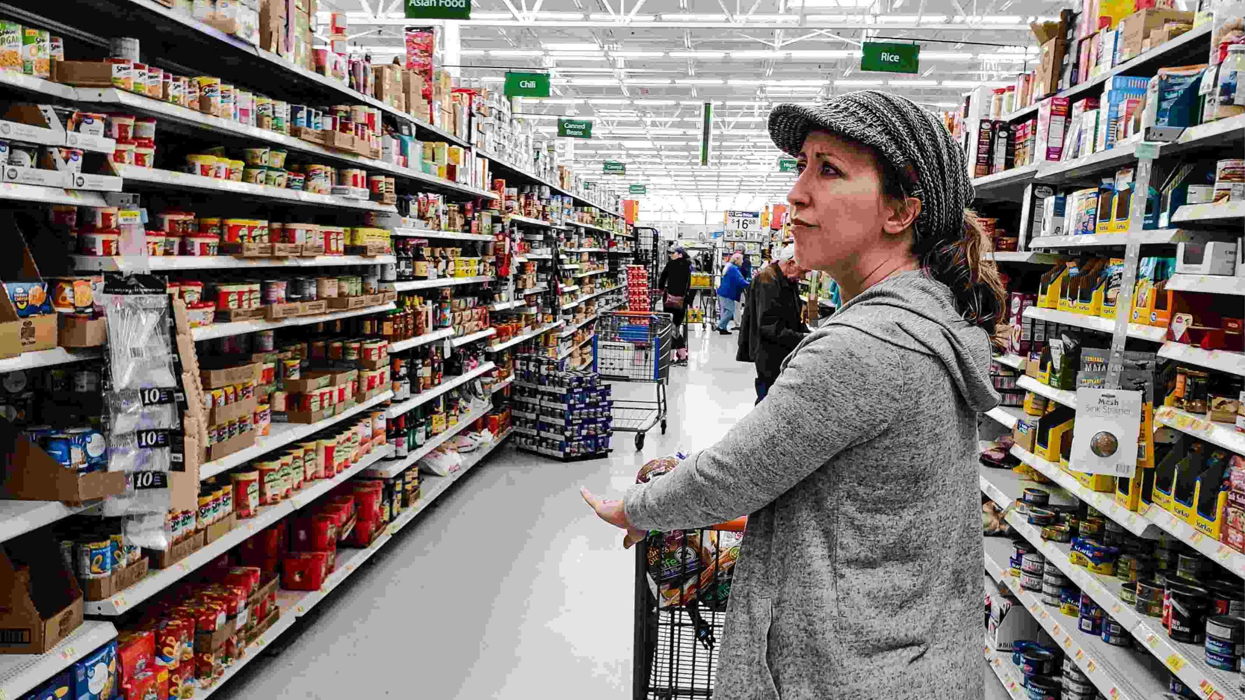 Shopper deciding between brands in a Walmart grocery aisle — the moment a food and beverage Walmart launch is won or lost